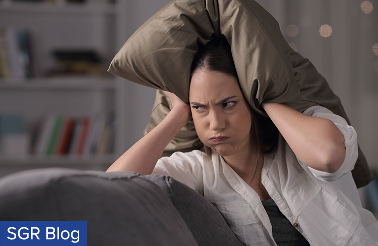 Woman with Pillow over Ears to Cover Noise