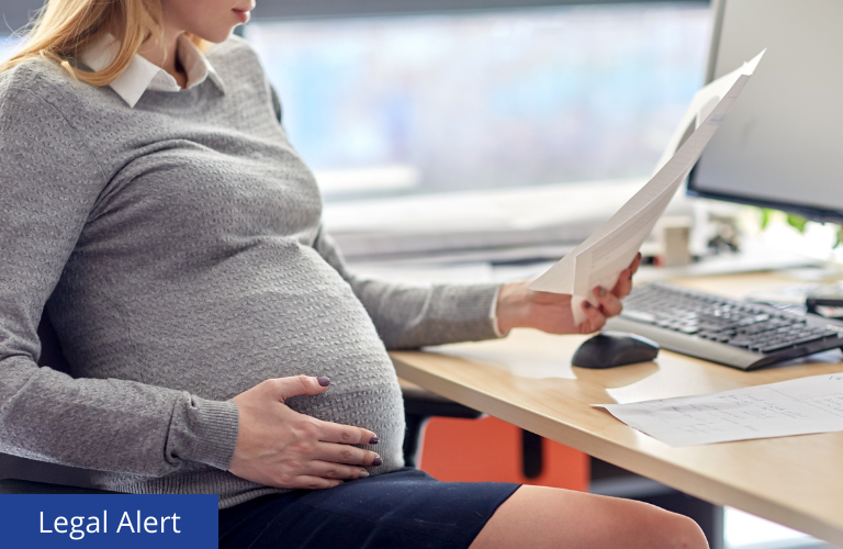 Pregnant office worker looking over paper work.